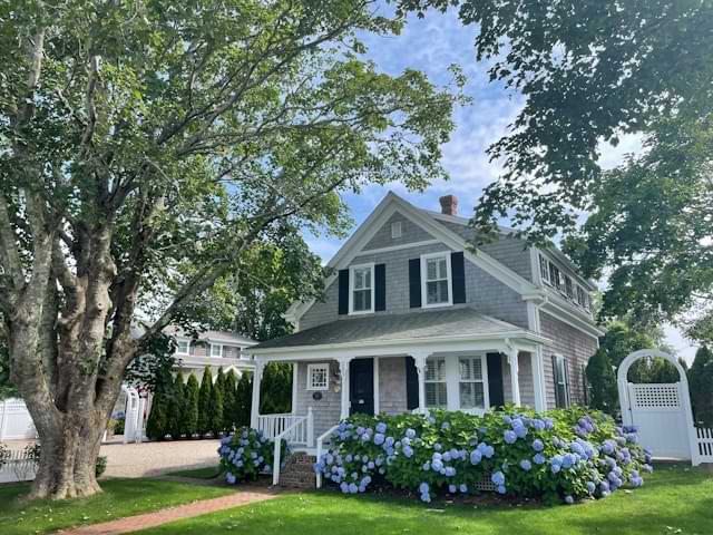 Cottage house with gray siding, white trim, and black shutters
