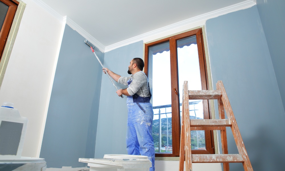 using a long roller to paint a room's wall