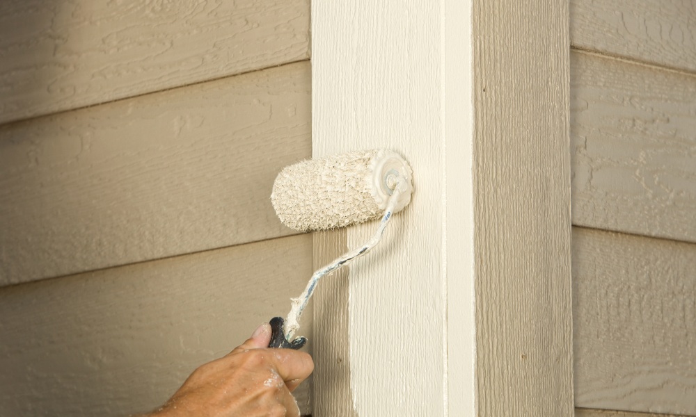 using a small paint roller to apply beige paint