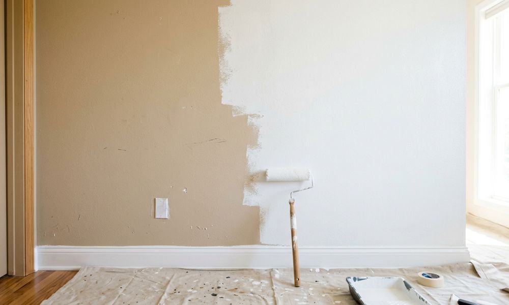 A paint roller resting against an interior wall being repainted