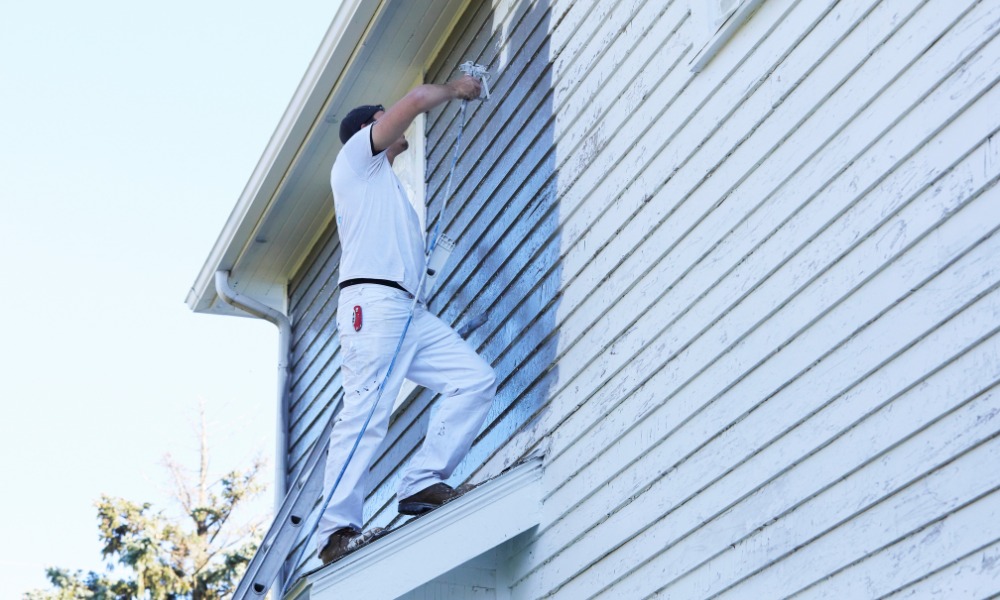 A house painter using a spray gun to apply fresh paint