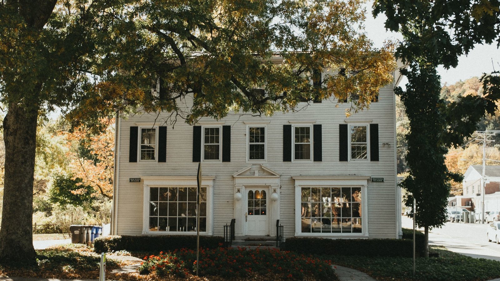 Colonial-style house in Connecticut surrounded by vibrant fall foliage, showcasing classic exterior paint durability.