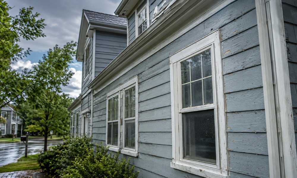 Faded, peeling grey wood siding on a house