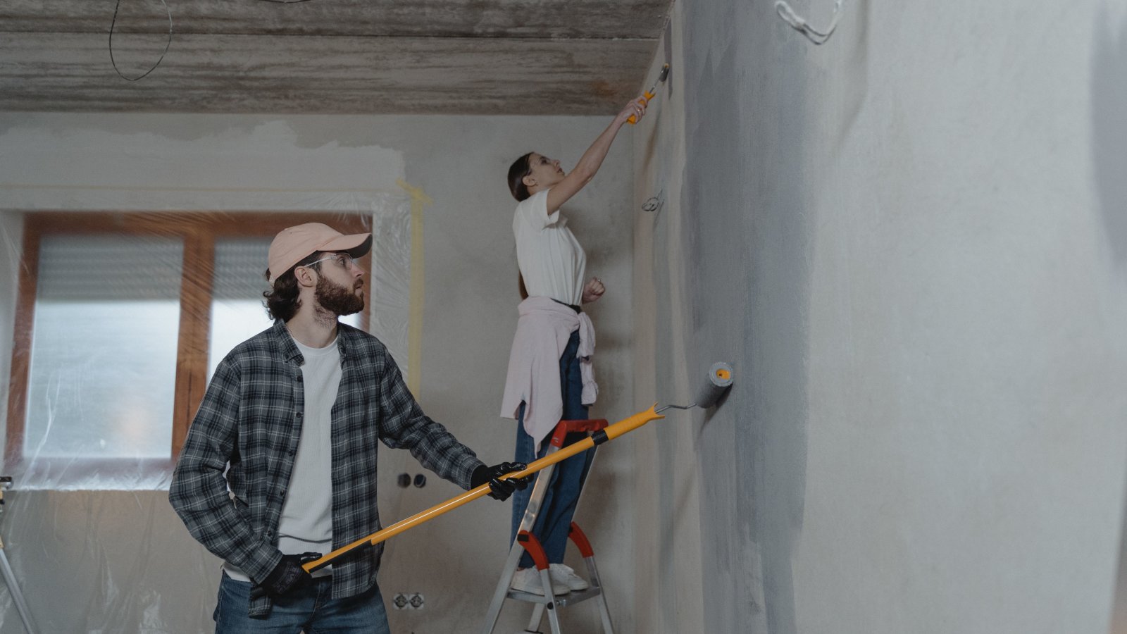 A couple painting a room together in a home interior during renovation.